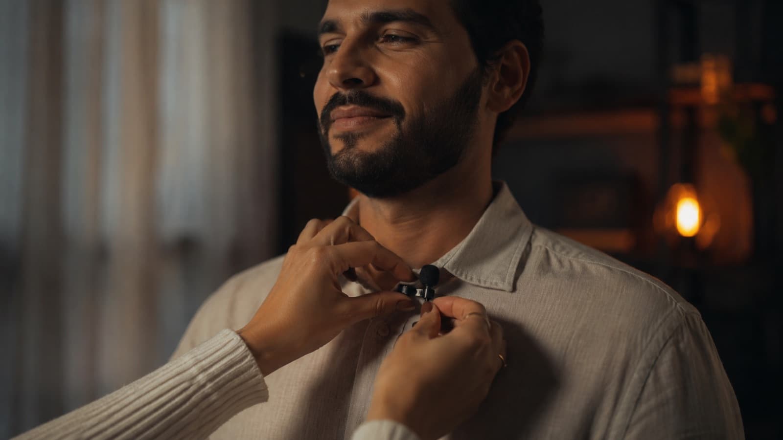 Mãos prendendo um microfone de lapela na camisa, bem perto da fonte
