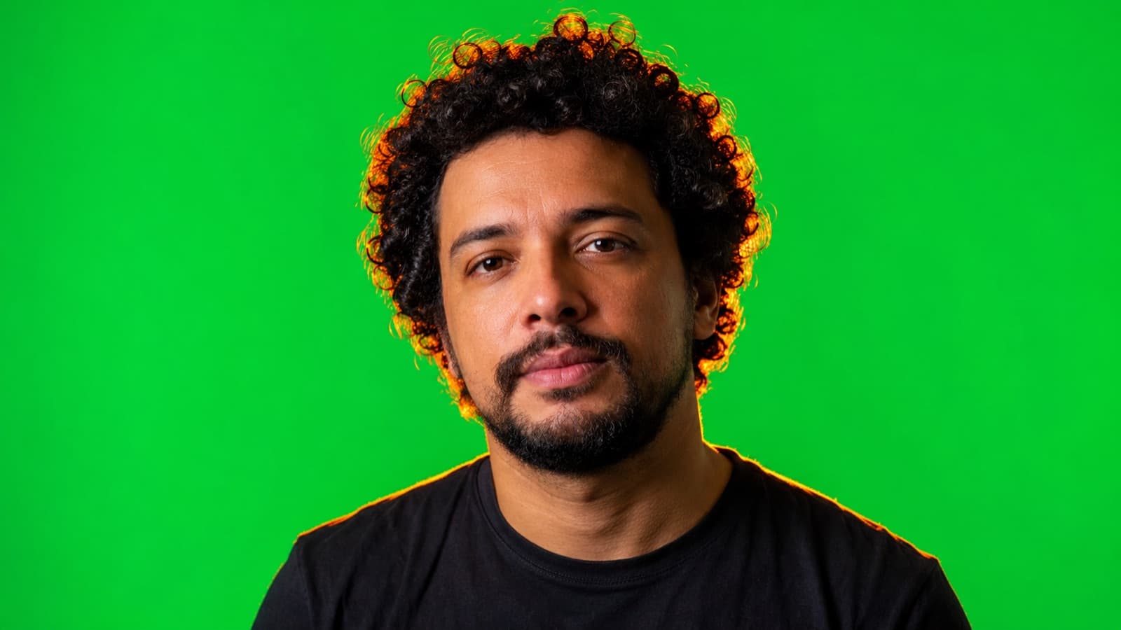 Pessoa em frente ao fundo verde com um contraluz laranja contornando o cabelo, matando o spill verde nas bordas