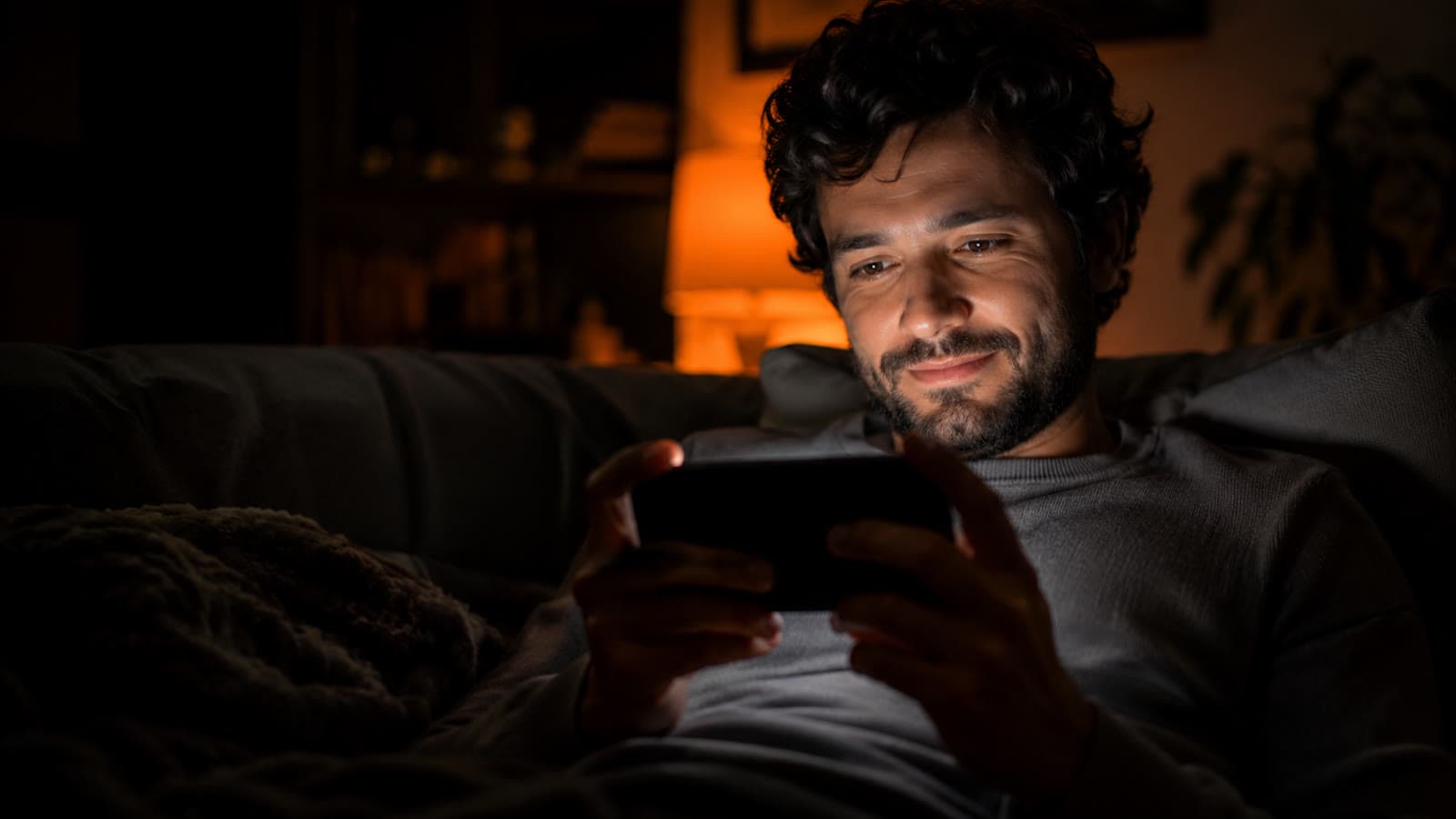 Aluno assistindo a uma aula no celular, à noite