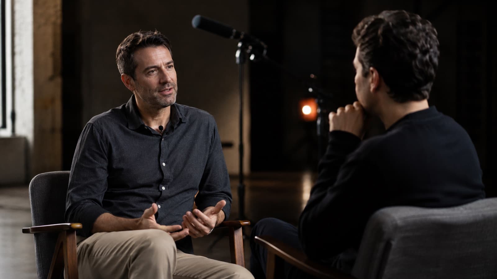 Cena real de entrevista com um microfone shotgun num suporte apontado para o entrevistado