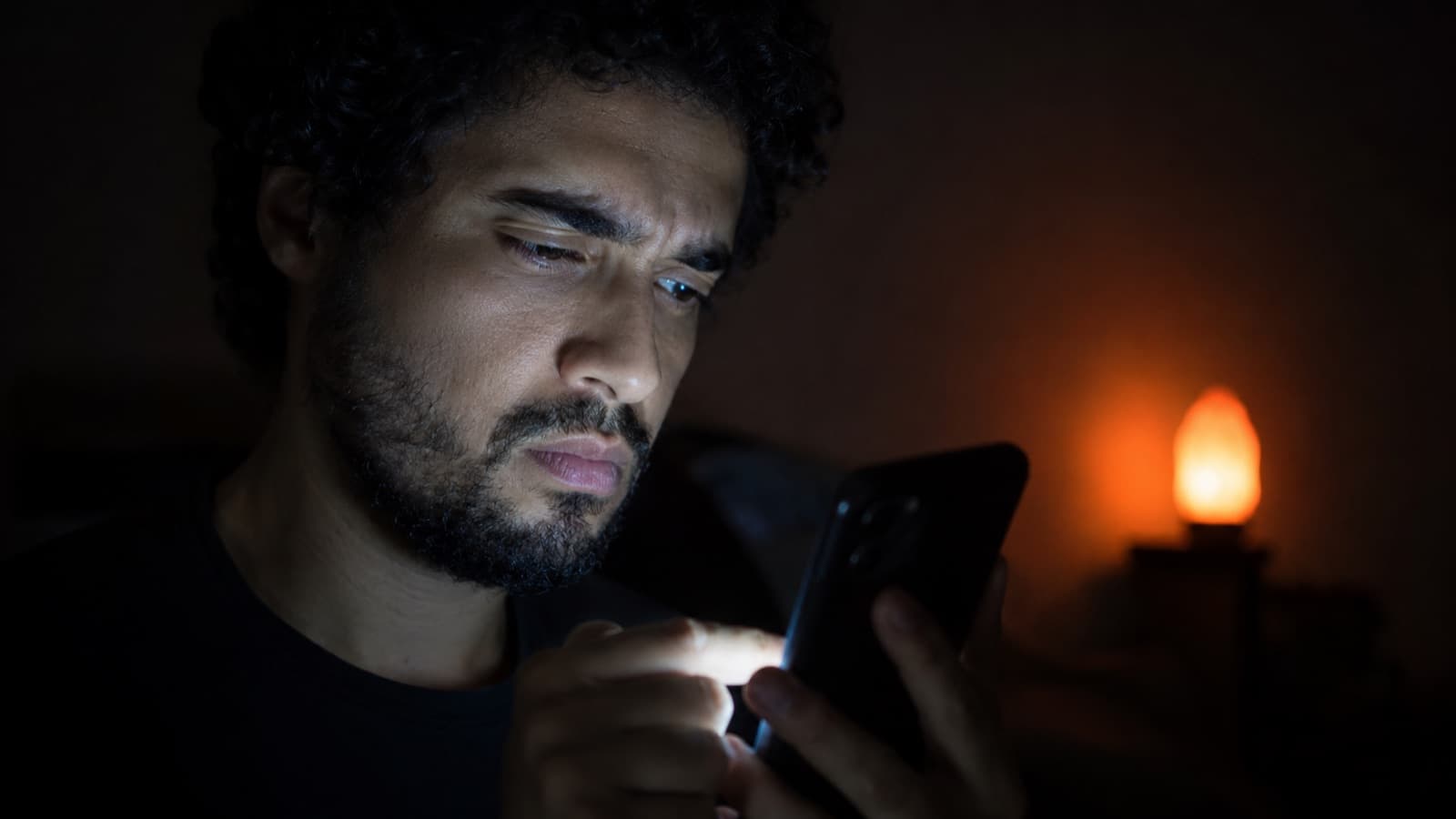 Pessoa assistindo ao celular com expressão crítica e impaciente, no escuro